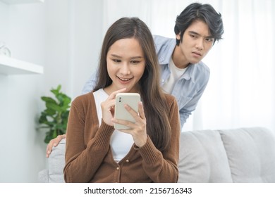 Infidelity, suspicion asian young couple love, wife using mobile phone, husband watching spying his girlfriend while woman chat a message, man sneaky distrust and jealousy, relationship problem.