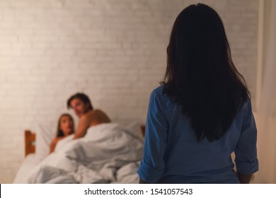 Infidelity. Wife Catching Cheating Husband With Mistress In Bed Making Love At Home. Selective Focus, Low Light
