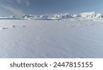 Infinitely, Infinitely polar snowy desert in Antarctica. South Pole frost surface. Scientific base. Snow covered mountains on horizon. Aerial view flight. Ice Landscape. Winter frozen ground drone fly