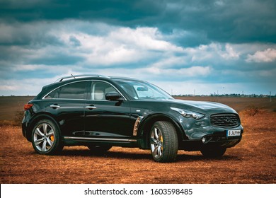 Infiniti FX50. Front side view of modern luxury black car xenon lamp headlight, LED fog lights. Beautiful cloudy sky reflection, carbon front grill, modern and prestigious SUV QX70. Extreme off road
