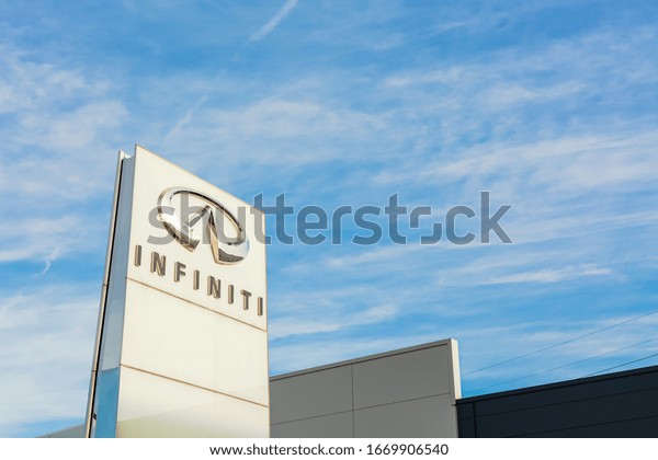 Infiniti Nissan Motor brand logo on bright blue sky\
background located on its car dealer office building in Lyon,\
France - February 23,\
2020