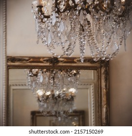 Infinity Concept. Antique Crystal Chandelier Reflected  Infinite Number Of Times In Old Mirror With Golden Frame. Grungy Luxurious Interior Vintage Abstract Background. 