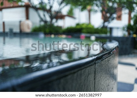 Infinity edge pool surface with clear water flowing over black tile in luxury resort