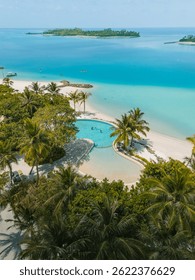 Infinity pool on a white sands beach with turquoise waters touching the ocean on a tropical island in Maldives