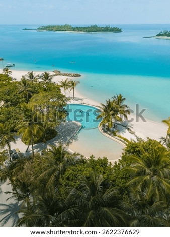 Infinity pool on a white sands beach with turquoise waters touching the ocean on a tropical island in Maldives