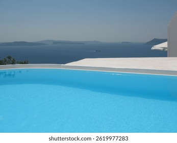 Infinity pool overlooking the Aegean Sea and nearby islands in Santorini, Greece. Bright blue water, clear skies, and minimalist architecture create a luxurious and serene summer atmosphere.