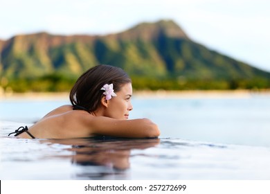 Infinity pool resort woman relaxing at sunset overlooking Waikiki beach in Honolulu city, Oahu island, Hawaii, USA. Wellness and relaxation concept for summer vacations.