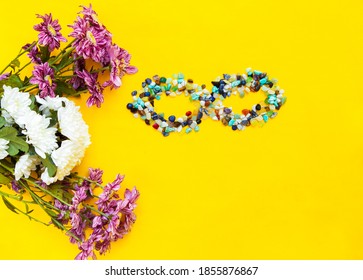 Infinity Symbol Made Of Stones With Flowers On A Yellow Background With Space For The Inscription