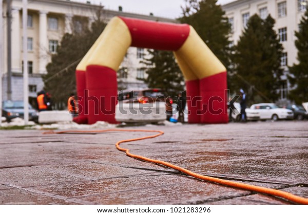The\
inflatable arch of red and orange color is used for start of auto\
racing and receives electricity on an orange\
wire