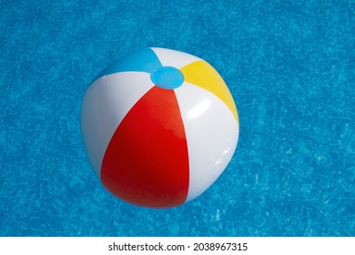 Inflatable beach ball afloat in swimming pool on a sunny summer day