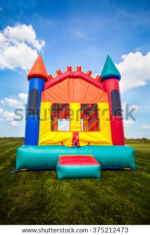 Inflatable bounce castle house in a large open yard.