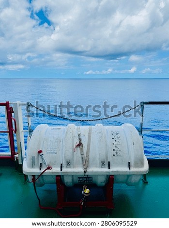 Inflatable emergency liferaft container securely mounted on the deck of a cargo ship, ready for deployment during emergency situations at sea with calm ocean behind