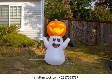 Inflatable Figure Of Ghost With Pumpkin Near The House. Outdoor Halloween Decoration