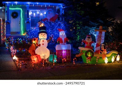 Inflatable figures of Santa Claus, elf and snowman glowing at night. Christmas and New Year holiday decorations. Selective focus, blurred background - Powered by Shutterstock