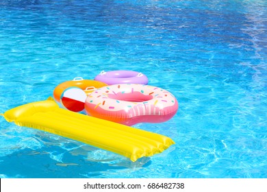 Inflatable mattress, donut and rings in blue swimming pool