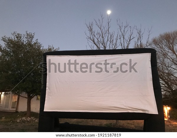 Inflatable outdoor wide movie screen with moon\
in backdrop
