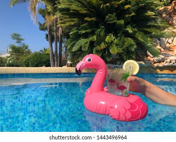 Inflatable Pink Flamingo Drink Holder And Woman's Hand In Swimming Pool