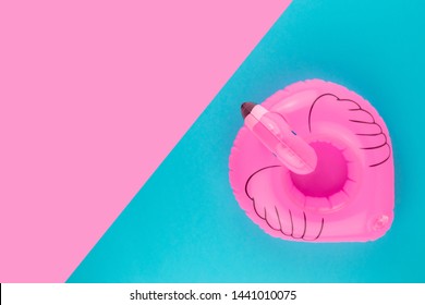 Inflatable pink flamingo on pastel blue and pink background. Summer beach composition. Flat lay, top view.