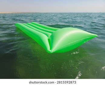 an inflatable pool float lounge mattress drifting on water, classic ribbed vinyl water rafts, with integrated raised pillow headrest, for sunbathing, lounging, and drifting on pool, lake, or beach waters
