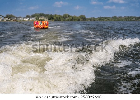 Inflatable raft being pulled at a high speed by a boat in a recreational activity called tubing