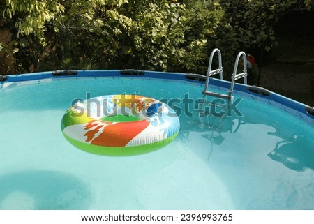 Inflatable ring floating on water in above ground swimming pool outdoors
