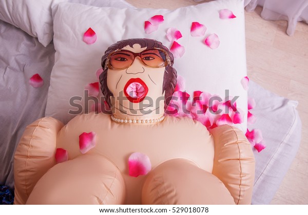 Inflatable sex\
doll strewed with petals of\
roses.