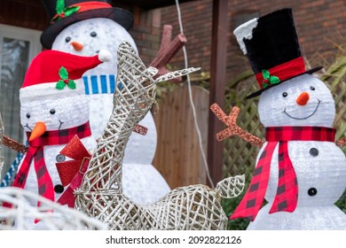 Inflatable Snowmen With Reindeer In Foreground To Celebrate Christmas, Photographed In A Suburban Garden In Windsor UK.