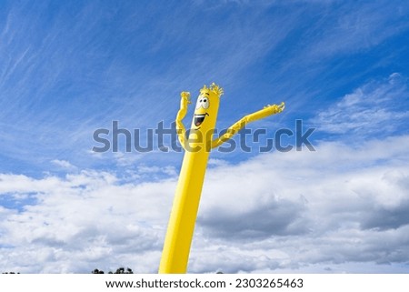 Inflatable wind doll against cloudy sky background.                              