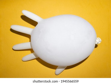 An Inflated Rubber Glove On A Yellow Background 