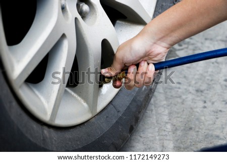 inflating tire and checking air pressure in service station.Filling air into a car tire at service center