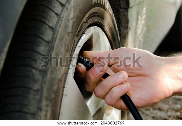 inflating the tire and checking the use of the air\
pressure gauge in the hands of the mechanic. Inflated rubber car\
tires. Close-up of a hand holding a car tire to measure the\
pressure of cars.