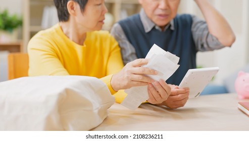 inflation concept - asian elderly couple look at receipt and shock about the price on bill in living room