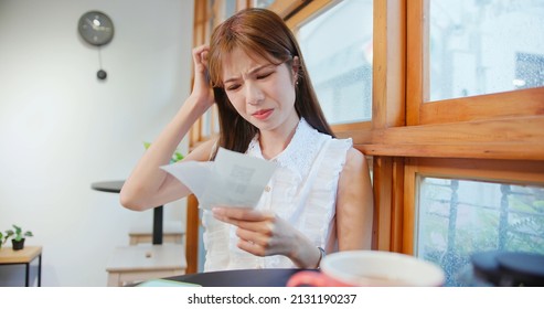 inflation concept - asian woman looking at her shopping receipt and shocked about the price in cafe