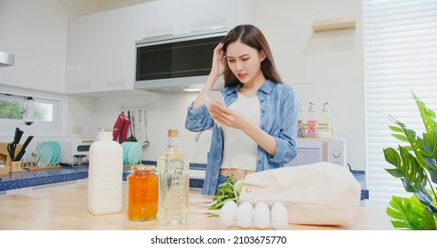 Inflation Concept - Worried Asian Woman Is Looking At Her Shopping Receipt From Her Cotton Eco Bag And Shocked About The Price At Kitchen