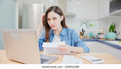 Inflation Concept - Worried Asian Woman Is Looking At Bill With Laptop At Home