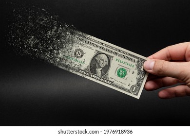 Inflation, dollar hyperinflation with black background. One dollar bill is sprayed in the hand of a man on a black background. The concept of decreasing purchasing power, inflation. - Shutterstock ID 1976918936
