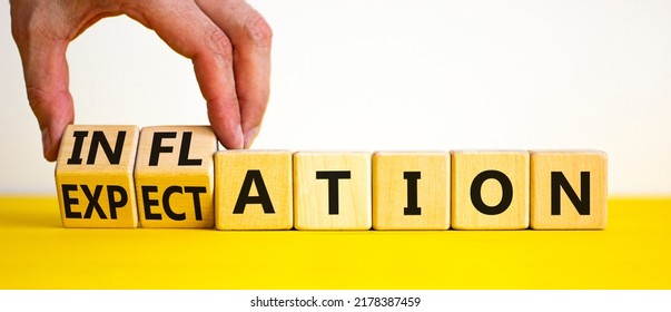 Inflation and expectation symbol. Businessman turns cubes, changes the word inflation to expectation. Beautiful yellow table, white background, copy space. Business, inflation and expectation concept.