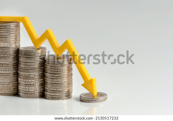 Inflation. The recession of the economy and the\
euro. The concept of economic collapse and the collapse of the\
stock exchange in the euro zone. Stacks of coins and a graph arrow\
pointing down.