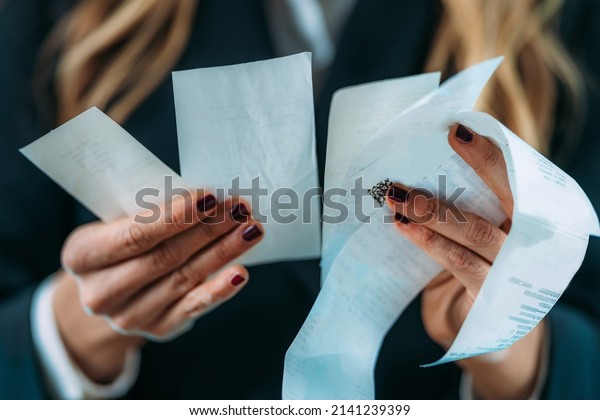 Inflation rising, costs\
increasing. Business woman holding Rising costs, declining standard\
of living, worried woman looking at increased costs on a printed\
receipt
