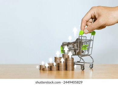 Inflation rising and goods price inflation. Shopping cart and a pile of coins with arrow on the chart is pointing up which indicates an impact on economic growth - Powered by Shutterstock