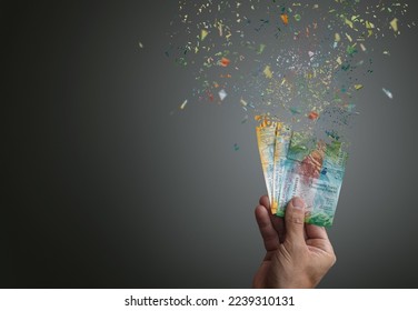 Inflation of swiss francs banknotes vanishing into nothing  Man hand holding 10 and 50 swiss francs dispersing into thin air or nothing  - Shutterstock ID 2239310131