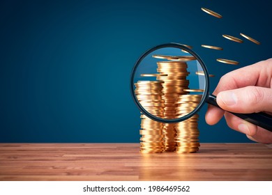 Inflation, tax, cash flow and another financial concept. Financial advisor focused on decreasing value of money in post-covid era. Hand with magnifying glass focused on coins fly away.