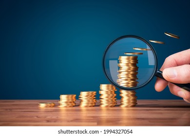 Inflation, tax, cash flow and another financial concept. Financial advisor focused on decreasing value of money in post-covid era. Hand with magnifying glass focused on coins fly away. - Shutterstock ID 1994327054