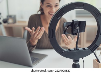 Influencer creating videos for social media, she is using a laptop, smartphone and ring light