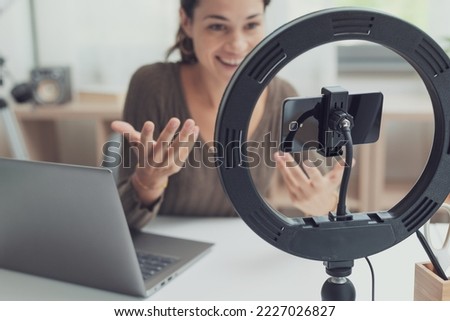 Influencer creating videos for social media, she is using a laptop, smartphone and ring light