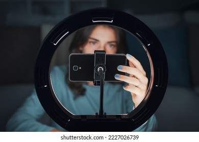 Influencer girl creating videos for social media at home, she is using a smartphone and a ring light - Powered by Shutterstock