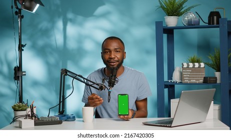 Influencer Holding Smartphone With Green Screen On Display While Filming Video For Podcast Channel. Blogger Using Phone With Isolated Background And Mockup Template For Social Media Vlog