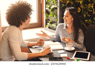 Informal job interview. Cheerful woman talking with new candidate in cafe, free space - Powered by Shutterstock