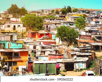 Informal Settlements (Slum), Huts Made Of Metal In The Township Or Cape Flats Of Stellenbosch, Cape Town, South Africa With Big Mountain And Blue Sky And Gold Light Background