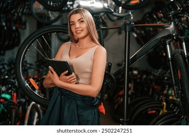 Information in the digital tablet, standing. Repair woman in bicycle shop, working in store. - Powered by Shutterstock